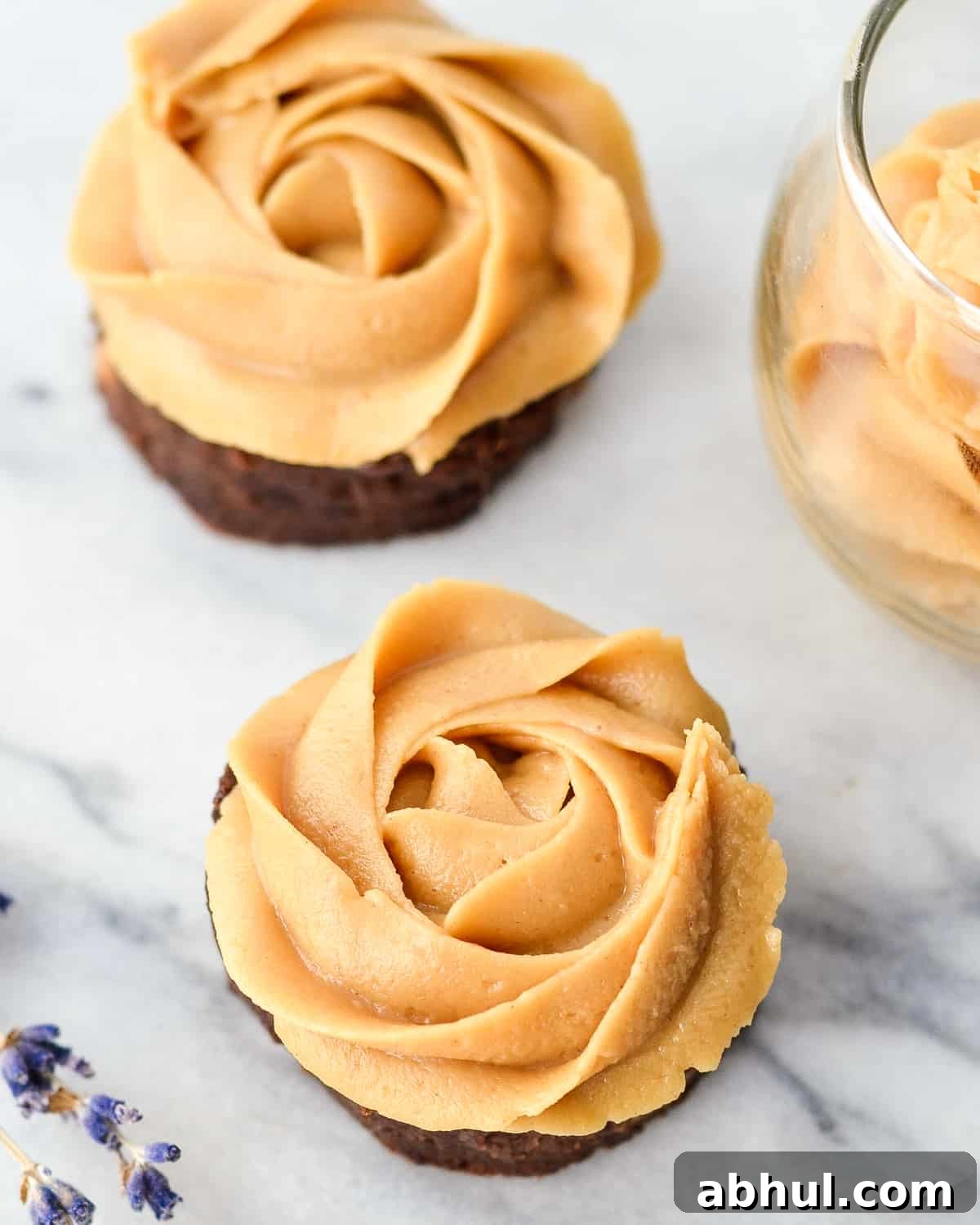 two brownies frosted with homemade vegan peanut butter frosting piped on in the shape of a rose 