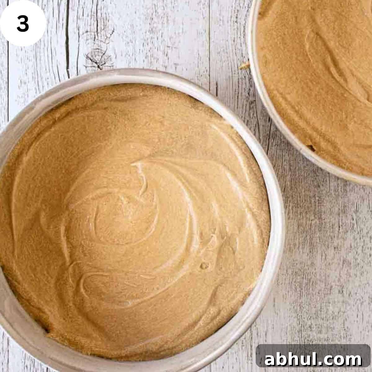 Cake batter divided into two round cake pans.