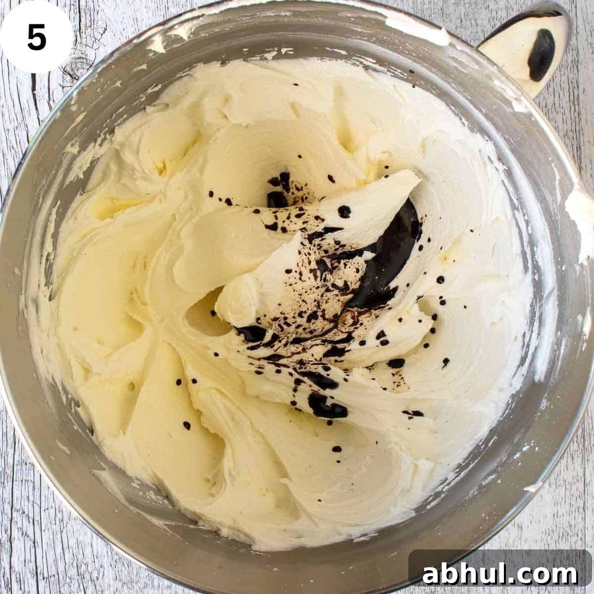 Small amount of dark liquid on creamy butter mixture in a bowl.