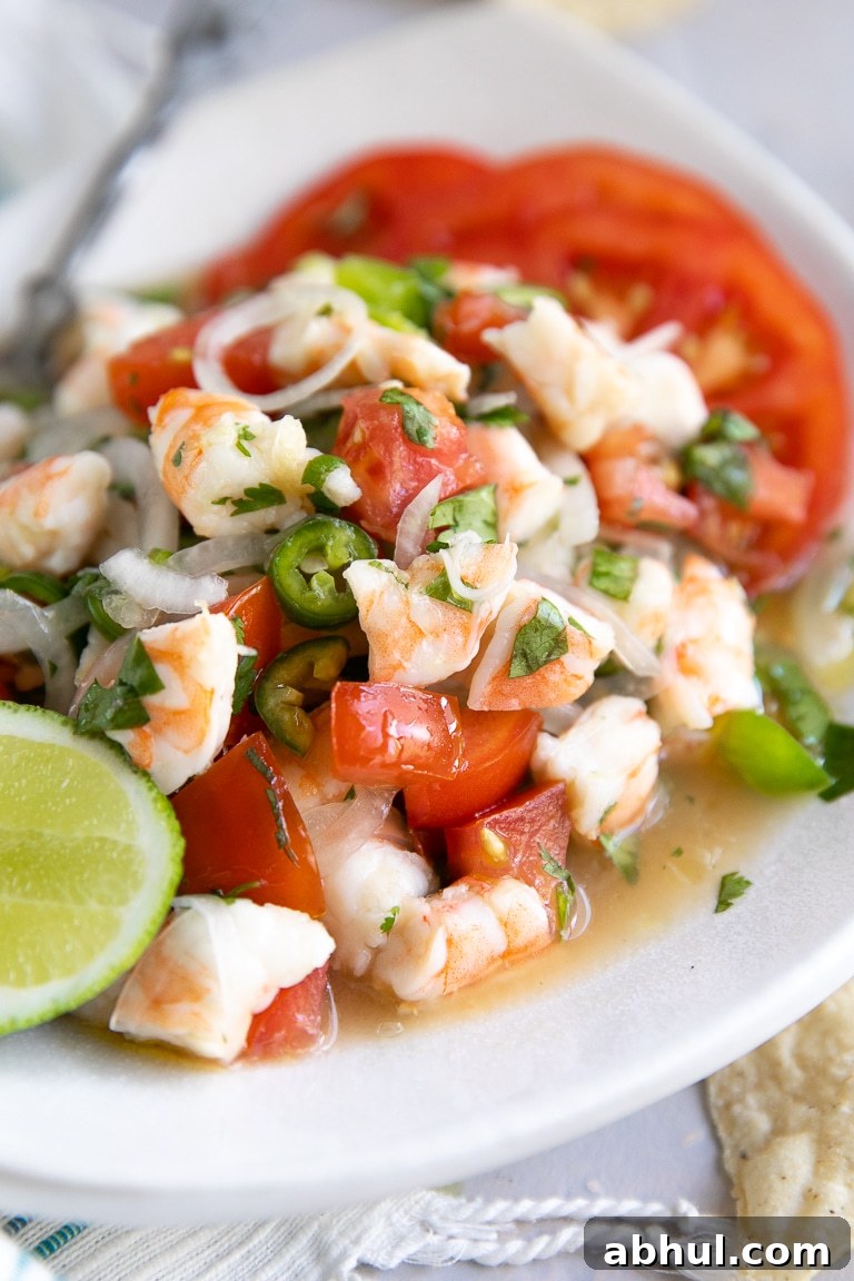 Small white plate filled with fresh shrimp and tomato ceviche.