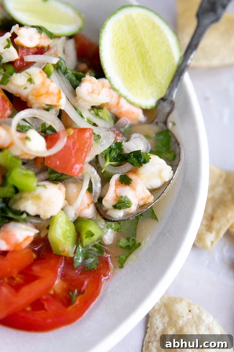 Spoon resting in a white dish filled with fresh shrimp ceviche.