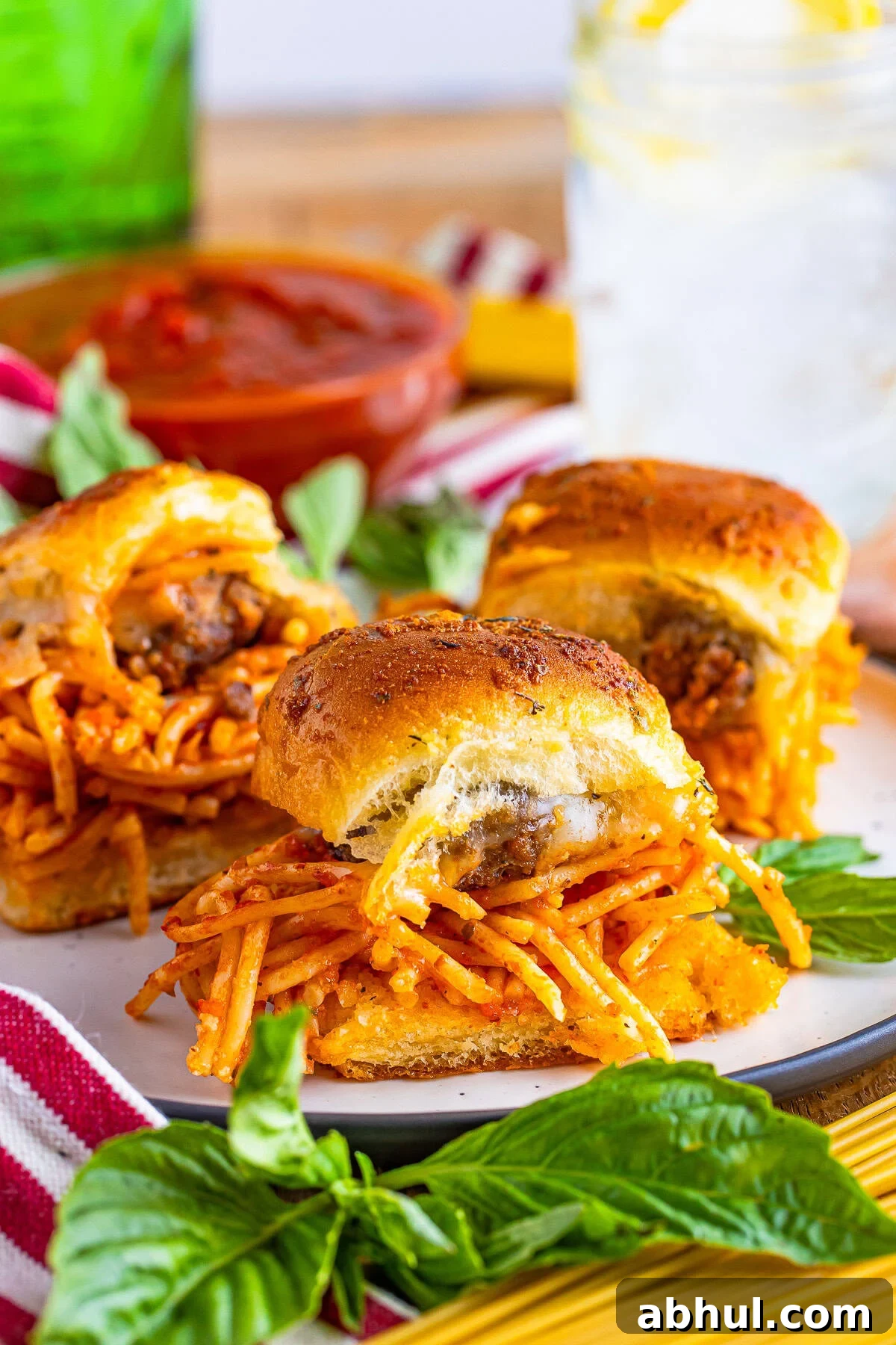 3 Meatball Sliders on a tan plate with basil