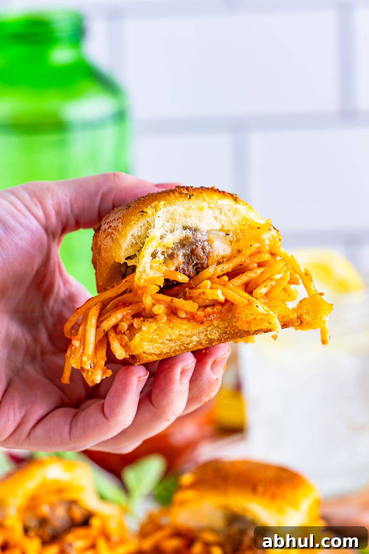 a hand holding up Meatball Sliders in air