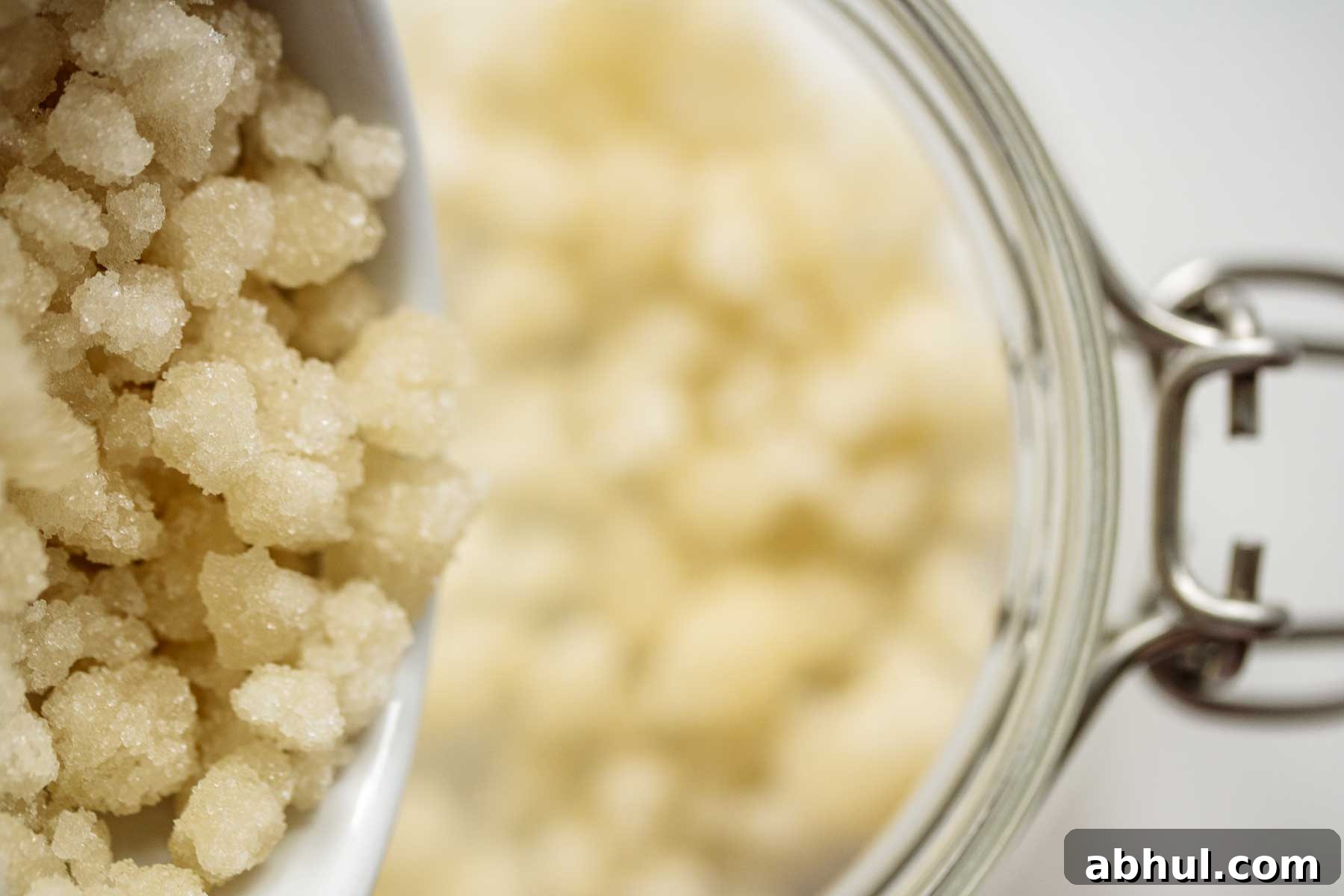Sugar pearls being dropped into a glass jar.