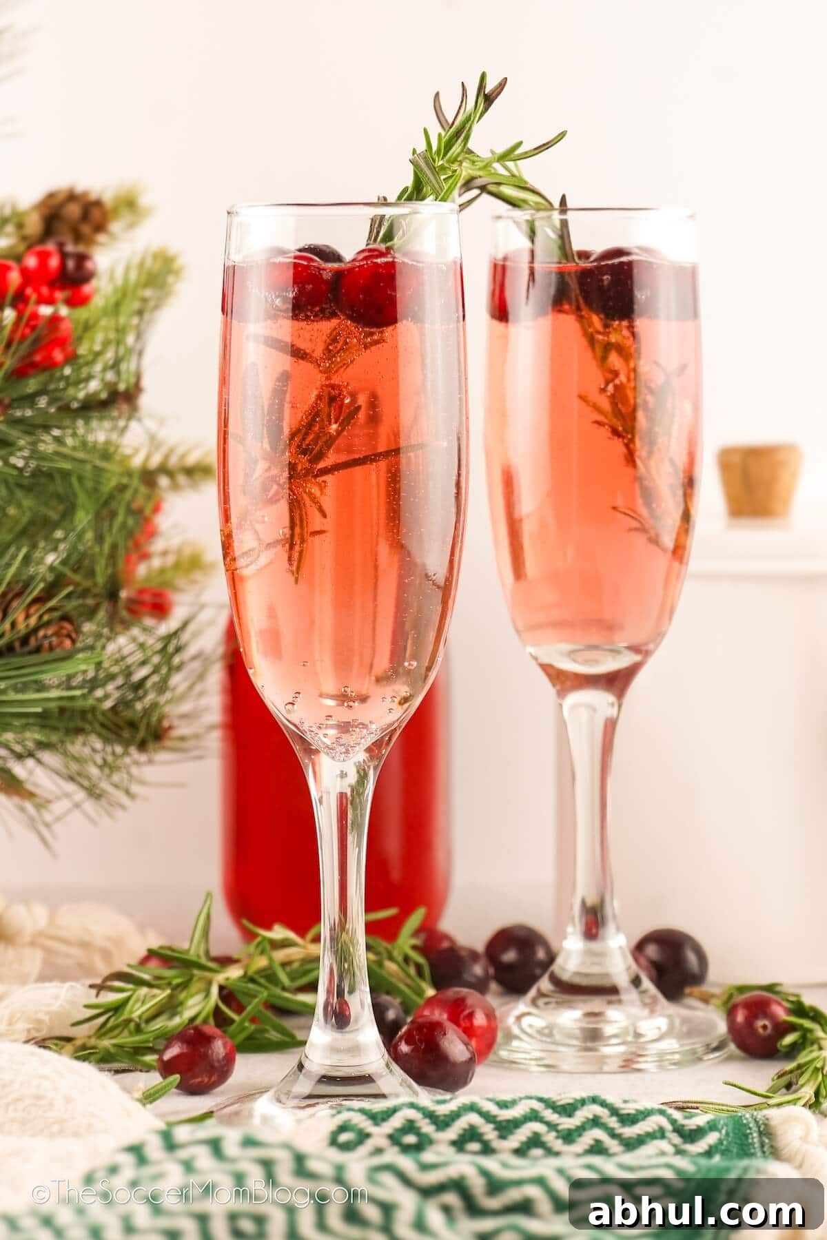 2 pink colored Christmas mimosas in champagne flutes.
