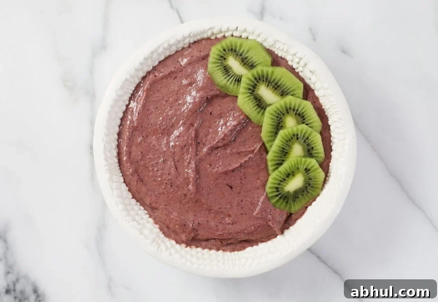 Process shot of adding fresh fruit to the top of the superfood berry smoothie bowl