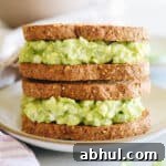 avocado egg salad on two sandwiches stacked on top of one another.