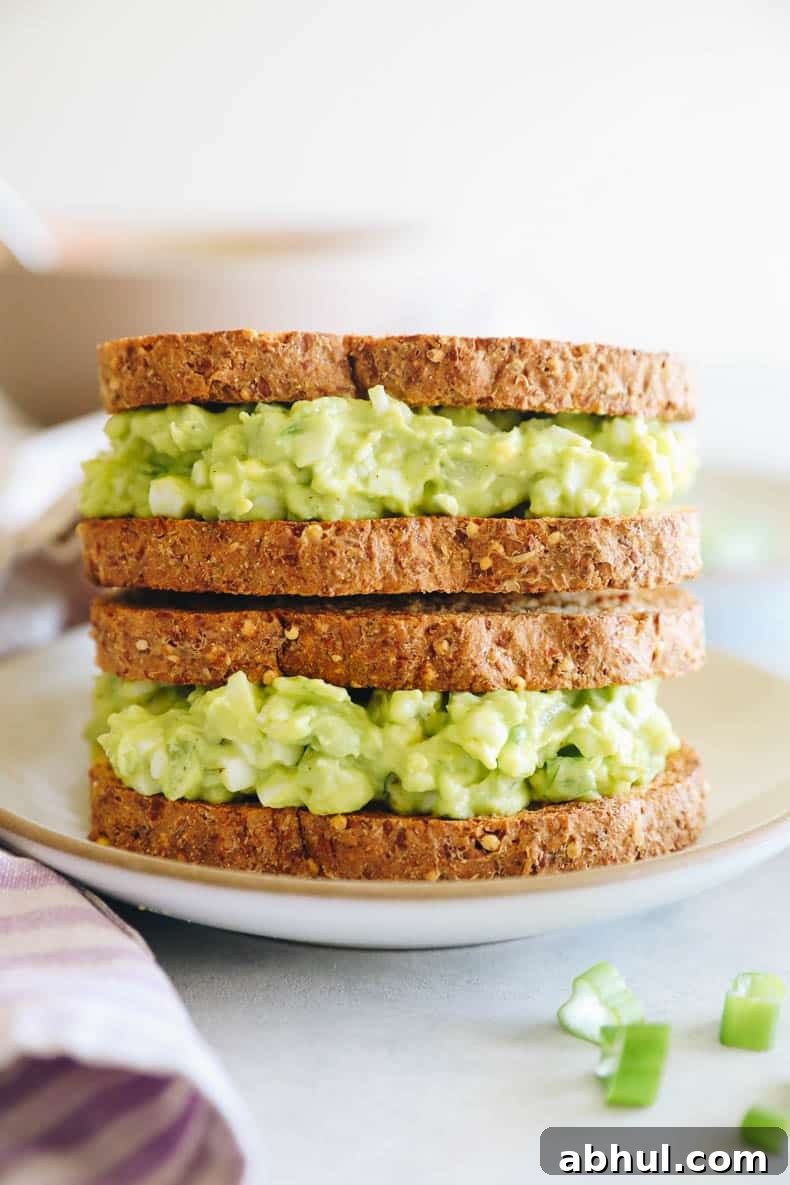 two avocado egg salad sandwiches stacked on top of each other.