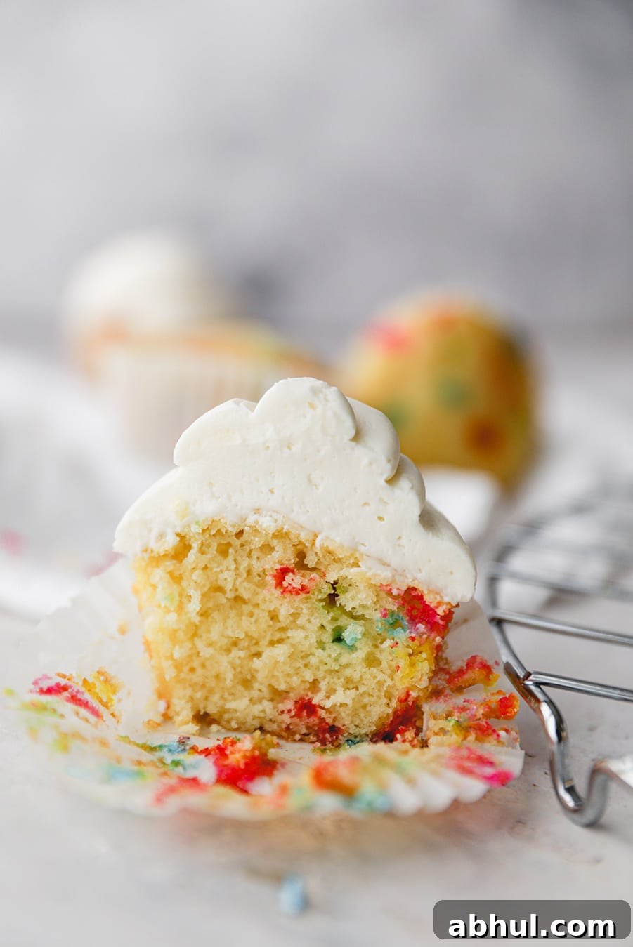Funfetti Cupcake Recipe: Colorful Sprinkles & Vanilla Frosting 3 funfetti cupcake sliced in half up close.