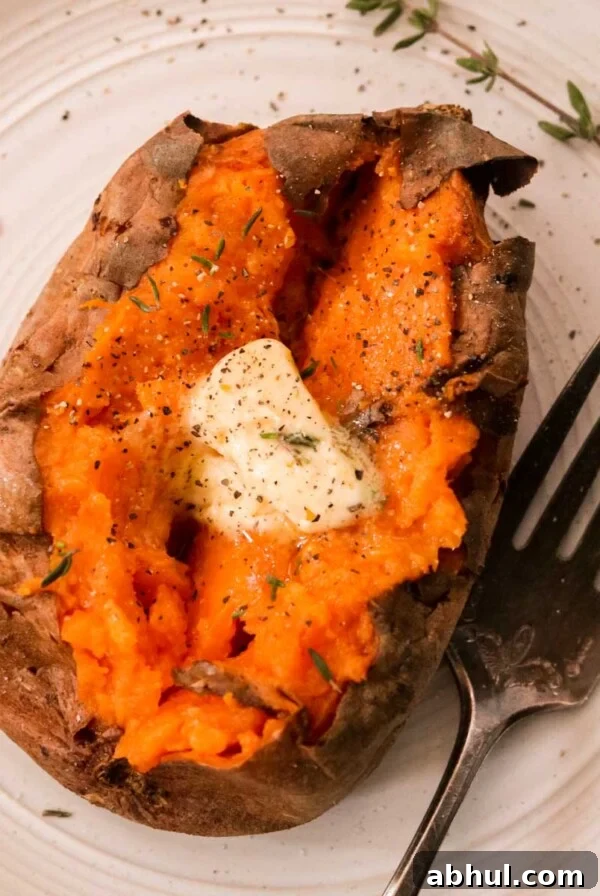 an overhead shot of a baked sweet potato topped with butter and fresh herbs