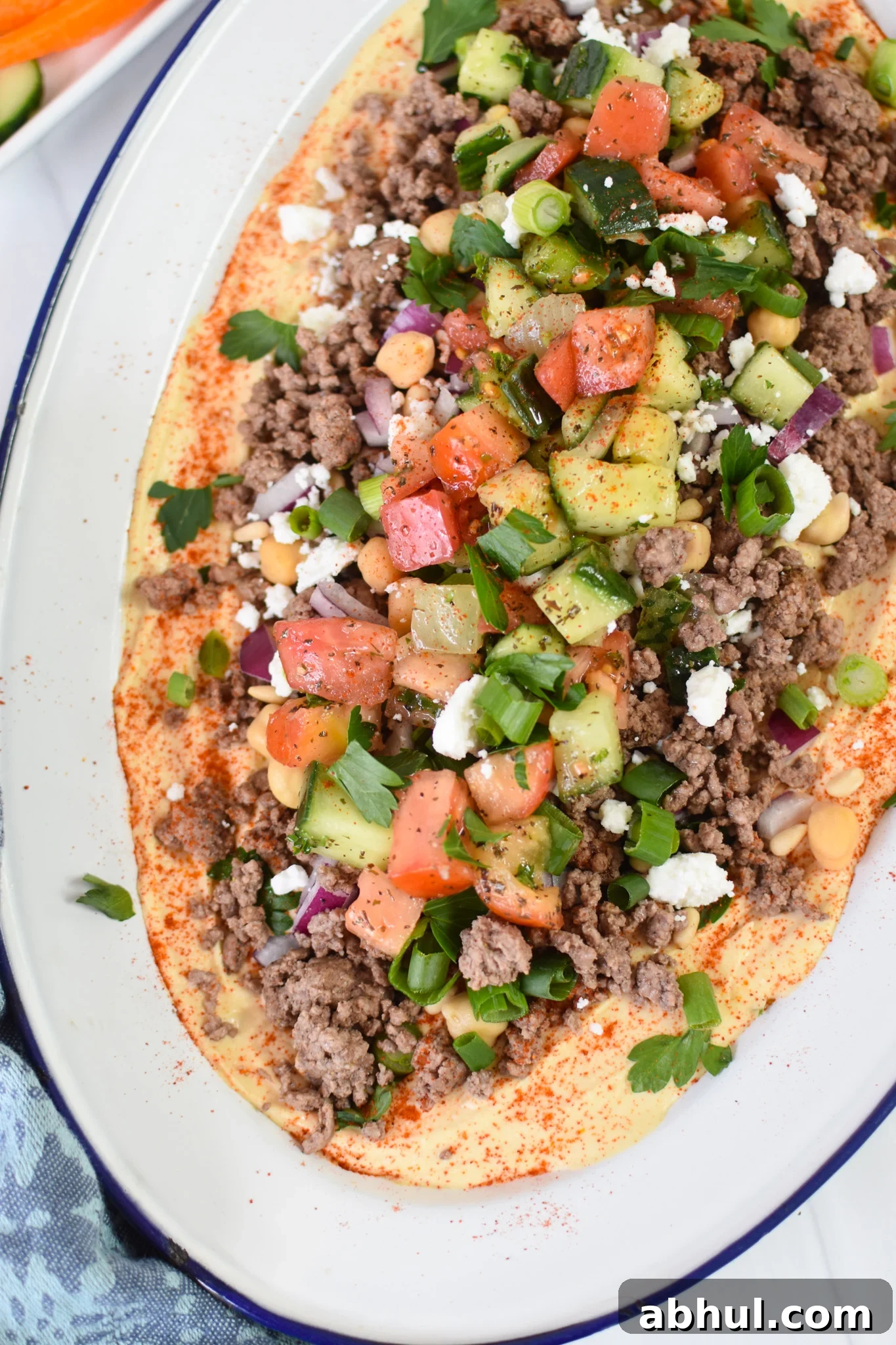 Ground Beef Layered Hummus on a white platter with blue rim.