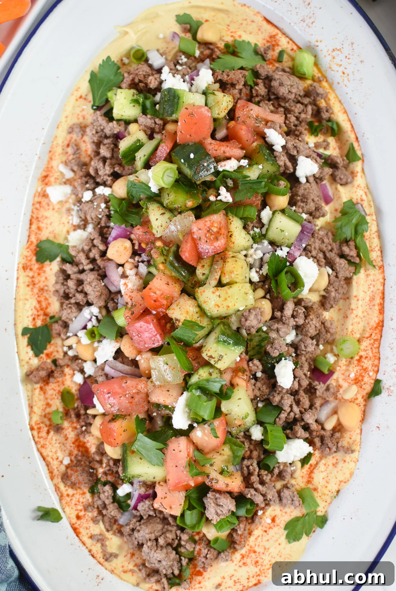 Ground Beef Layered Hummus with garnishes. 