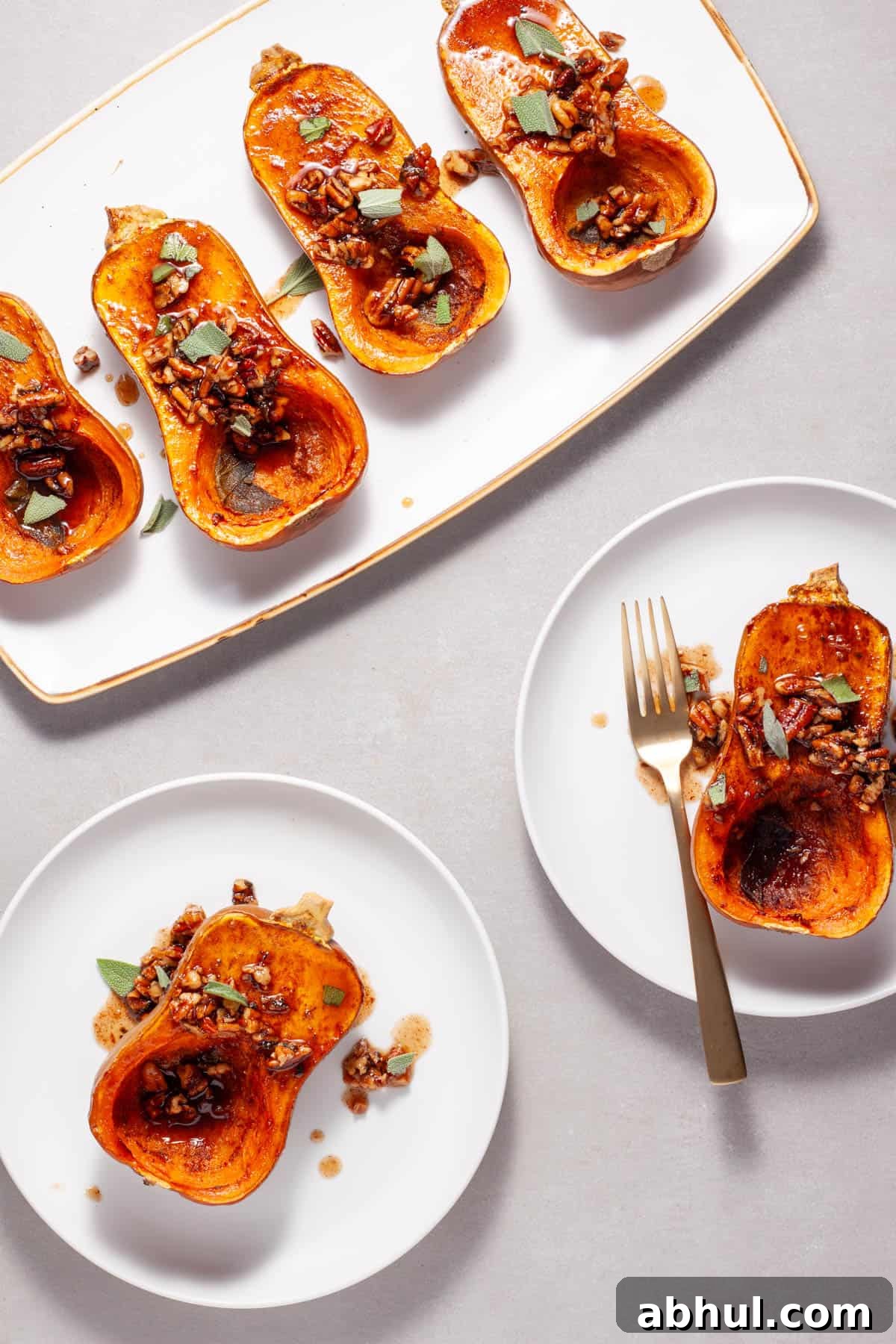 Maple-Pecan Roasted Honeynut Squash Recipe 10 Roasted honeynut squash with maple pecans on a serving platter with a couple portions on smaller plates.