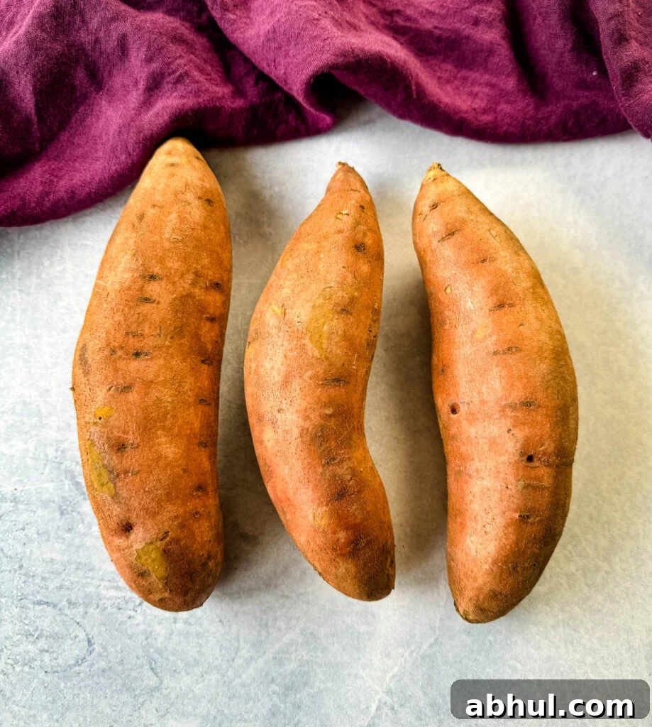 Crispy Fried Sweet Potatoes with Honey and Cinnamon 3 raw sweet potatoes in skin on a flat surface