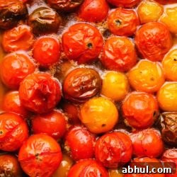 Juicy red tomatoes cooked in oil, showing rich and glossy textures.