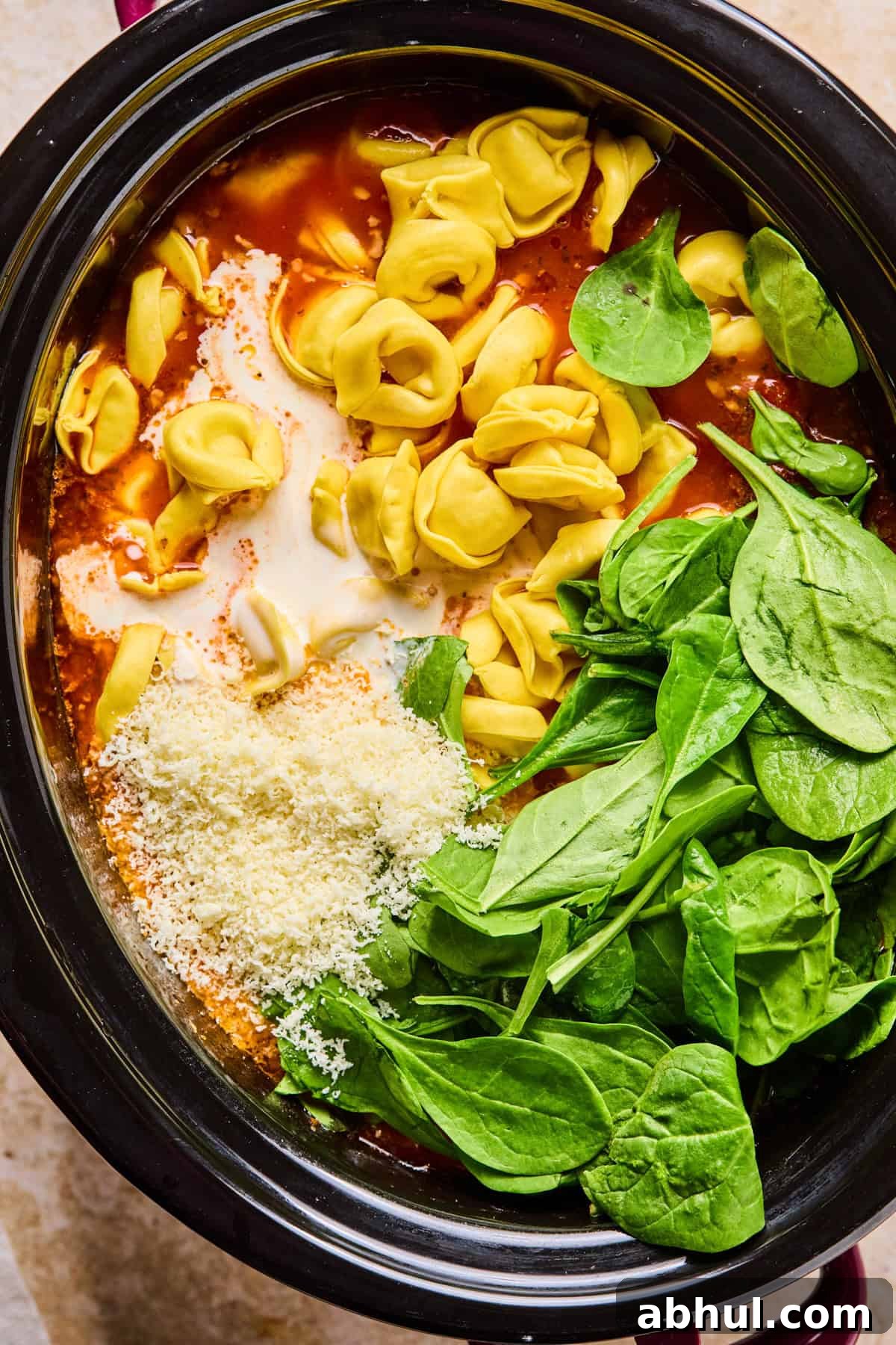 Tortellini, spinach, cream and parmesan added to soup in crockpot.