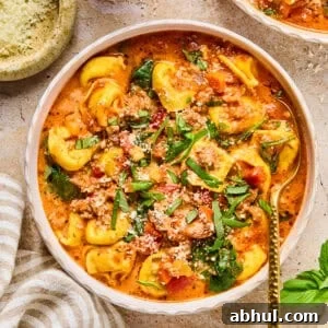 Crockpot sausage and tortellini soup in bowl with spoon.