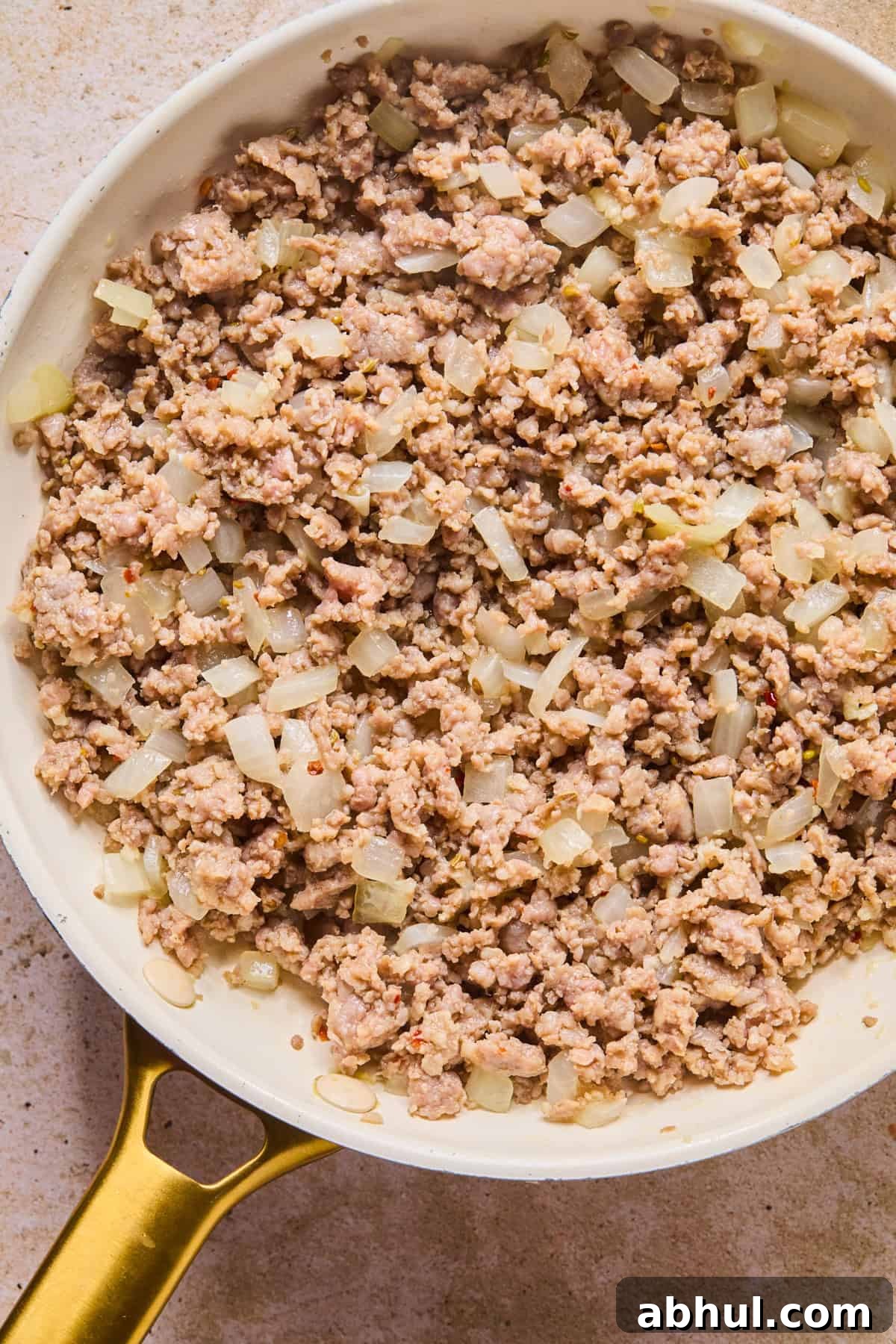 Browned Italian sausage in skillet with onions.