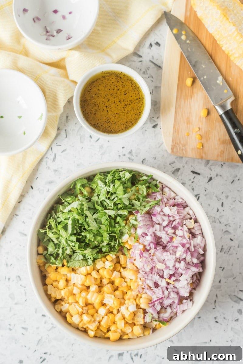Making fresh corn salad process of making fresh corn salad with corn, onion and basil in a white bowl with dressing displayed on the side