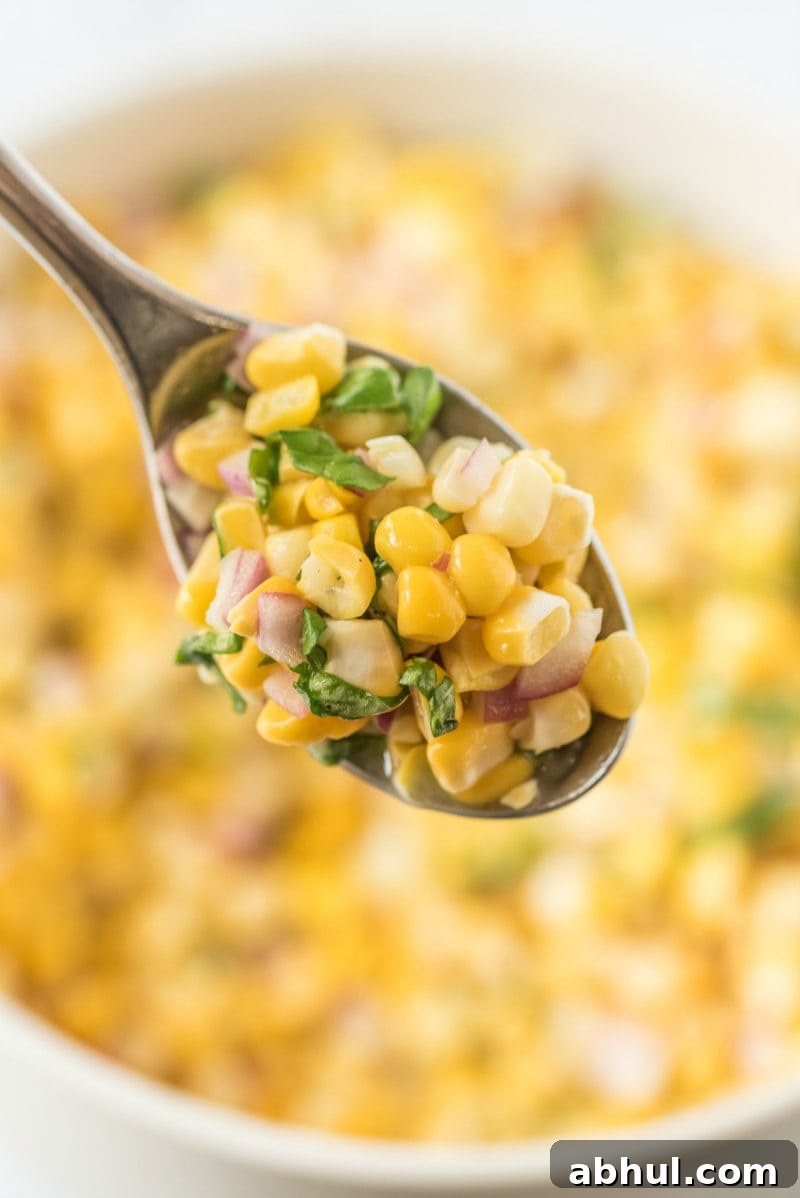 Spoonful of fresh corn salad spoonful of fresh corn salad above a white bowl of corn salad
