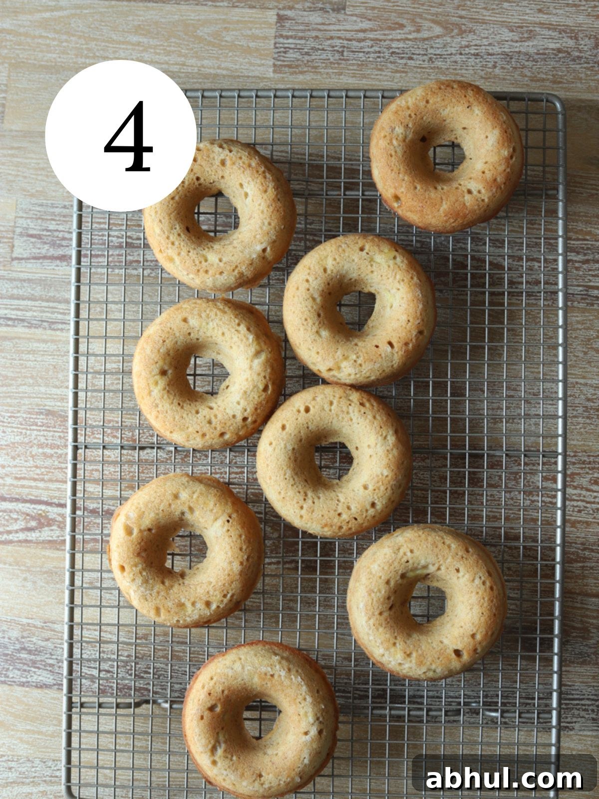 Baked donuts on a wire cooling rack on a wooden table.