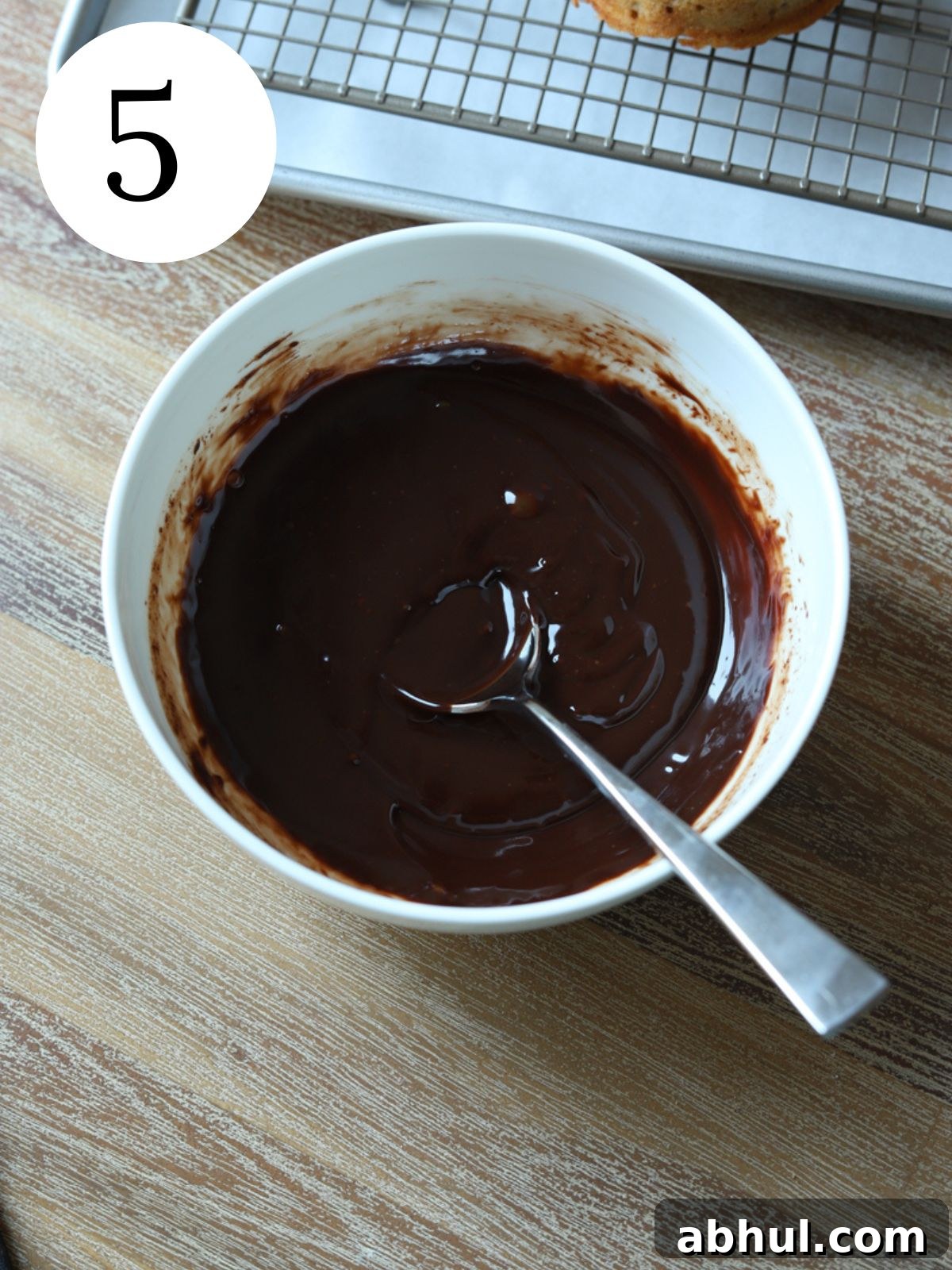 A white bowl with chocolate ganache and a spoon.