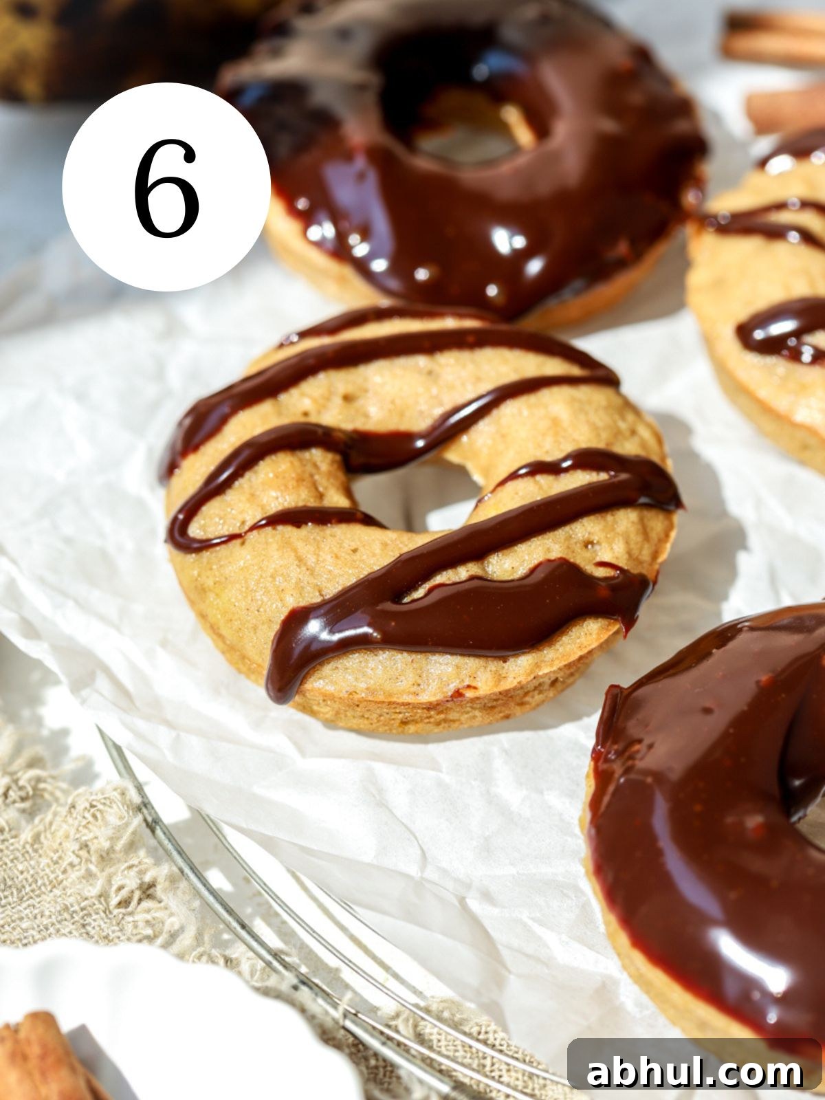 Donuts with chocolate ganache on top on parchment paper.