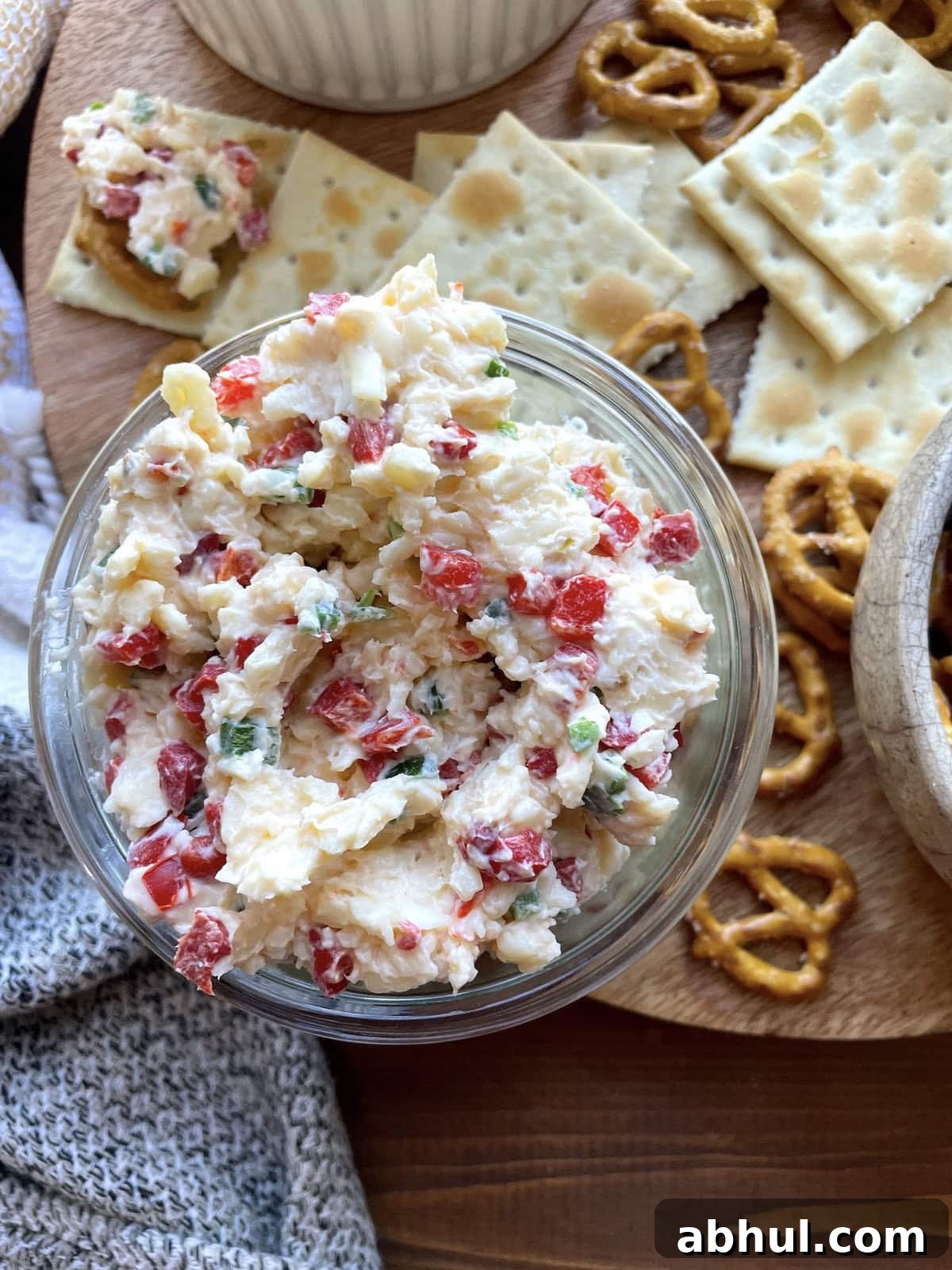 A bowl of spicy pimento cheese surrounded by saltines and pretzels.