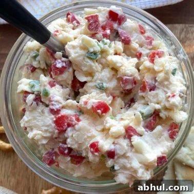 A bowl of creamy jalapeño pimento cheese made with white cheddar cheese with a spoon.