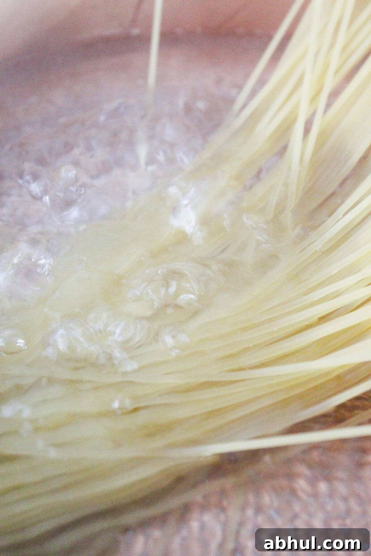 Uncooked spaghetti noodles being added to a pot of boiling water.
