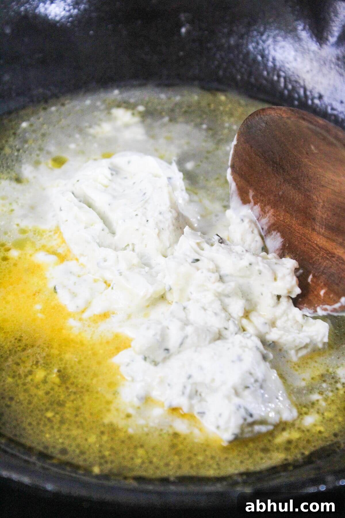 A spoon stirring food in a pan.