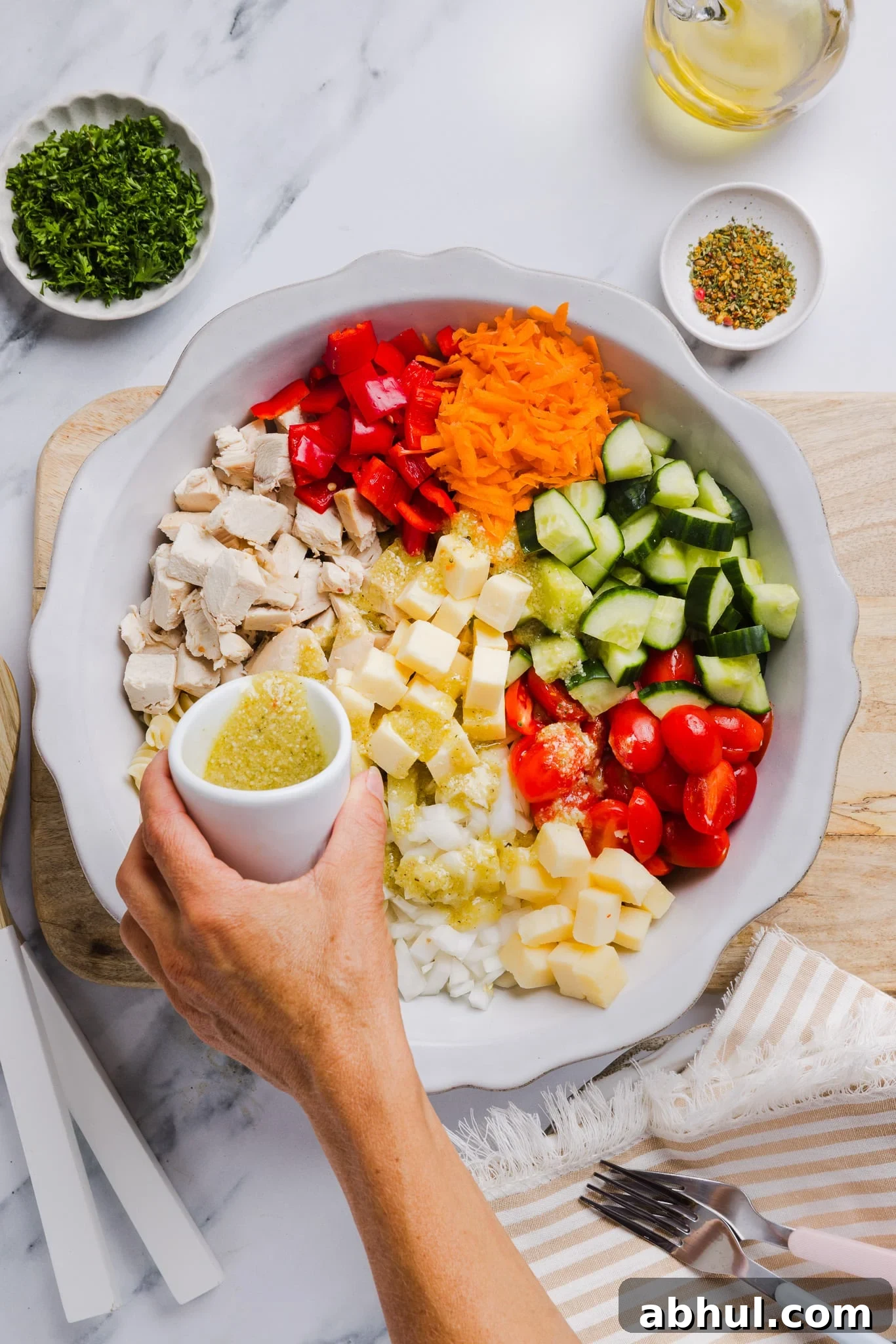 Ingredients for high protein pasta salad in a large bowl with dressing being poured on top.