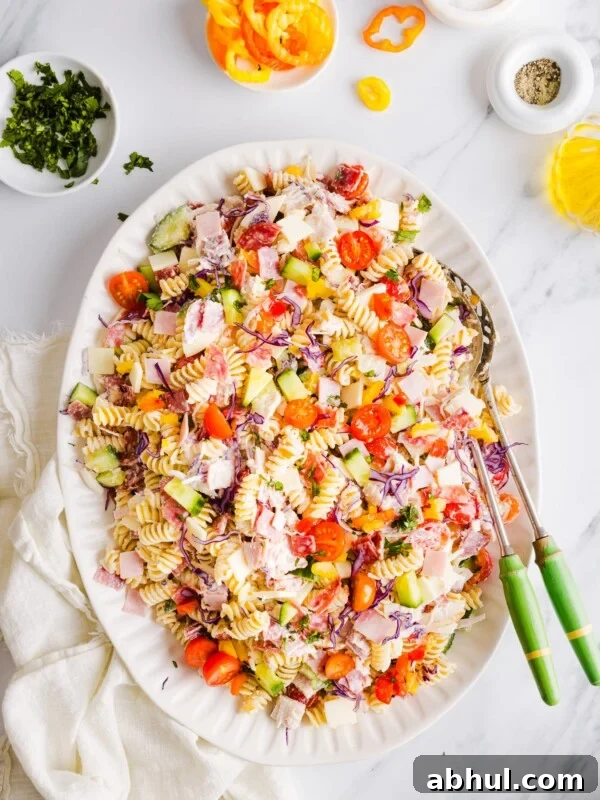 Grinder pasta salad on a large white platter with two serving spoons.