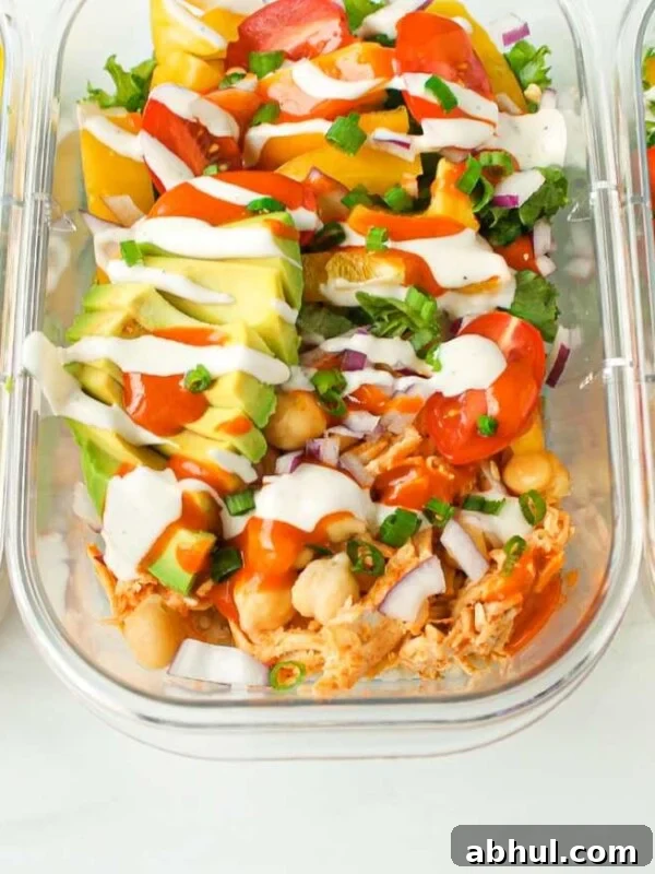 Three containers of buffalo chicken rice bowls lined up on a countertop.