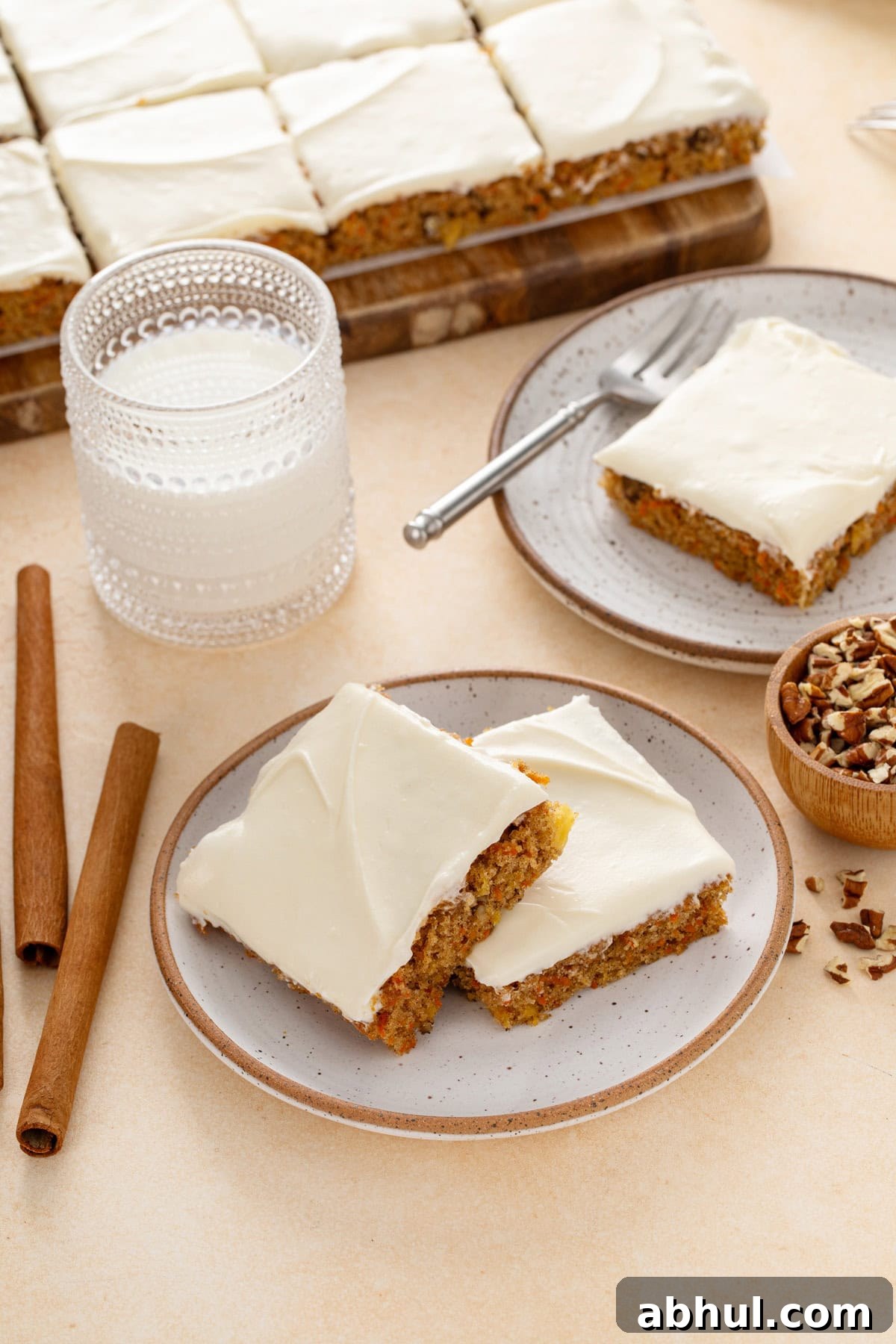 Plated carrot cake bars next to a glass of milk.