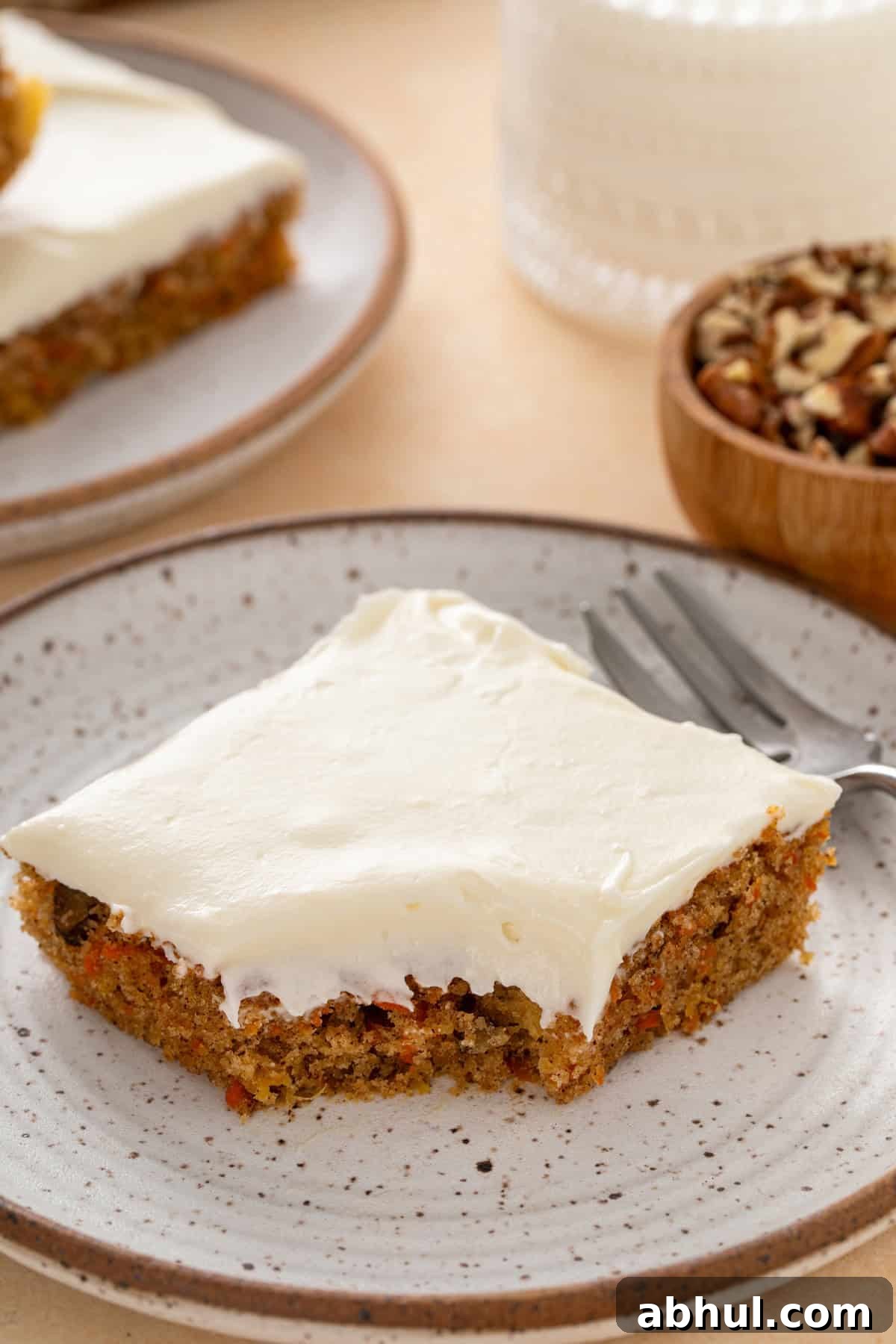 Bite from a carrot cake bar on a plate.