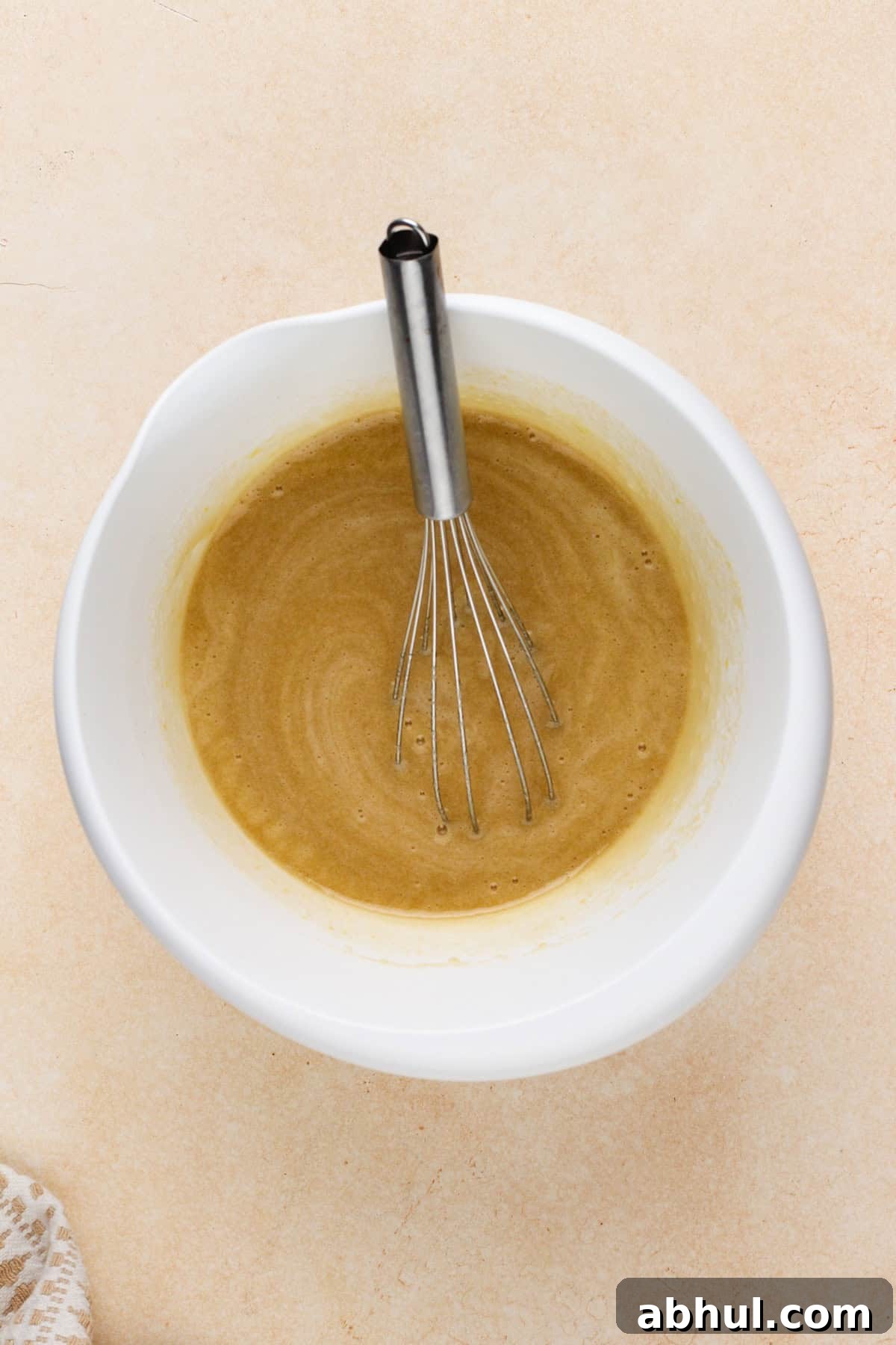 Wet ingredients for carrot cake bars whisked in a white bowl.