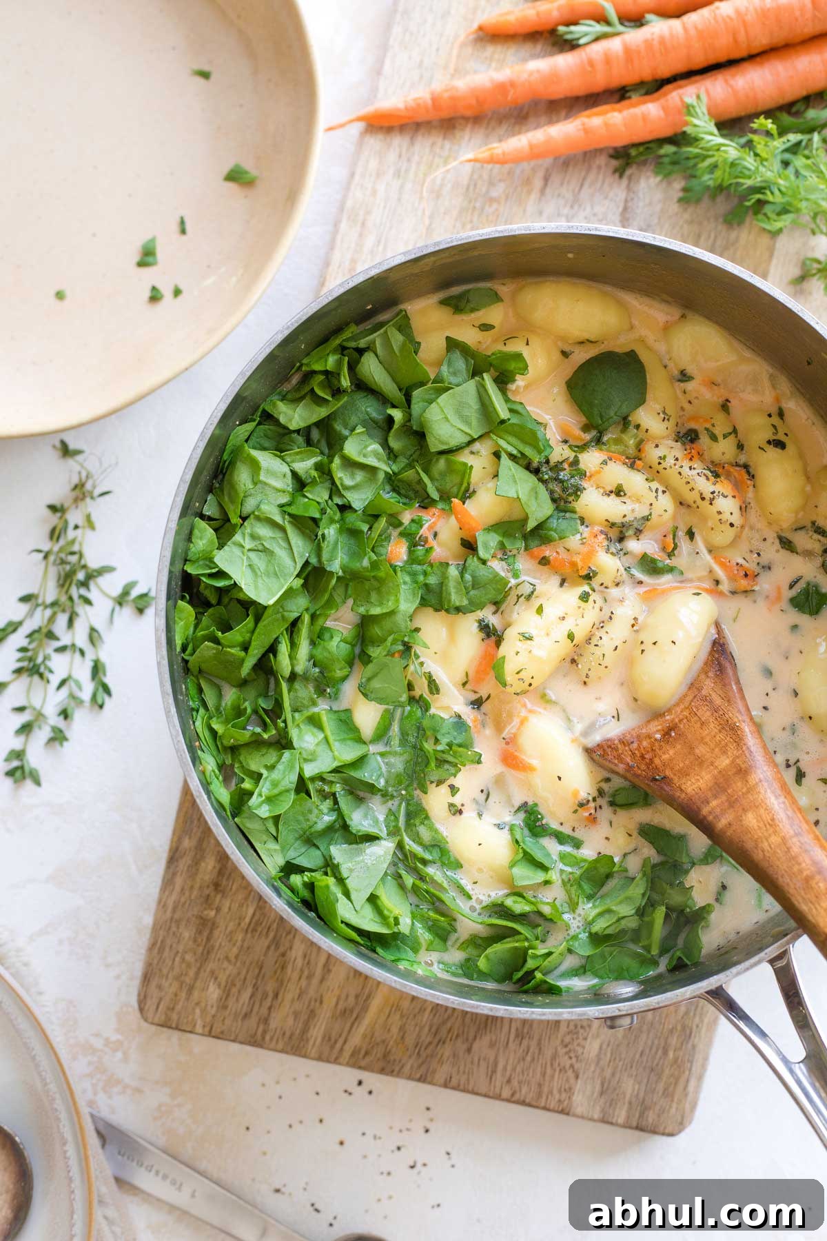 Overhead of a wooden spoon in soup pot, ready to stir in the spinach, salt and pepper.