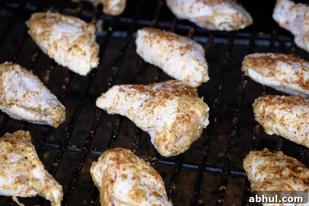 Marinated chicken wings on grill grates of a smoker.