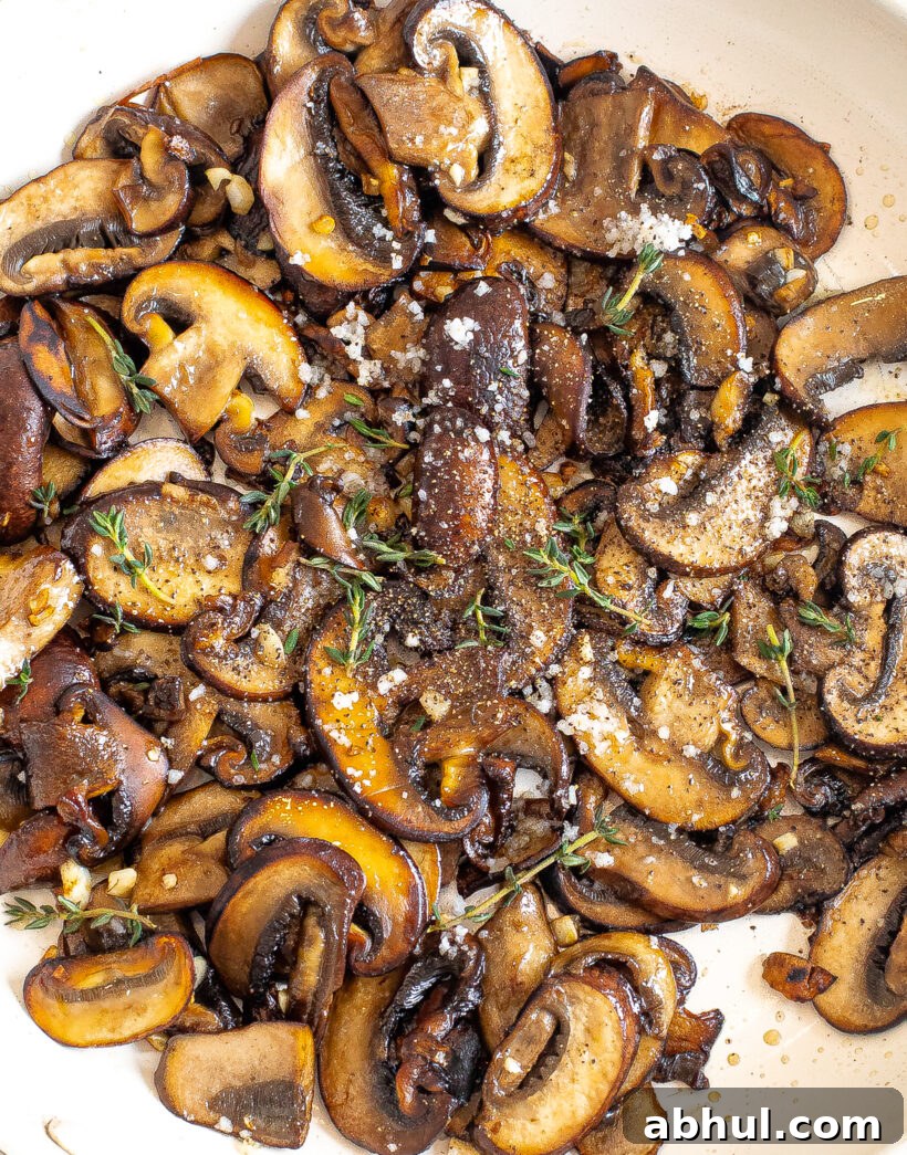 Sauteed mushrooms with garlic in a skillet topped with thyme. 