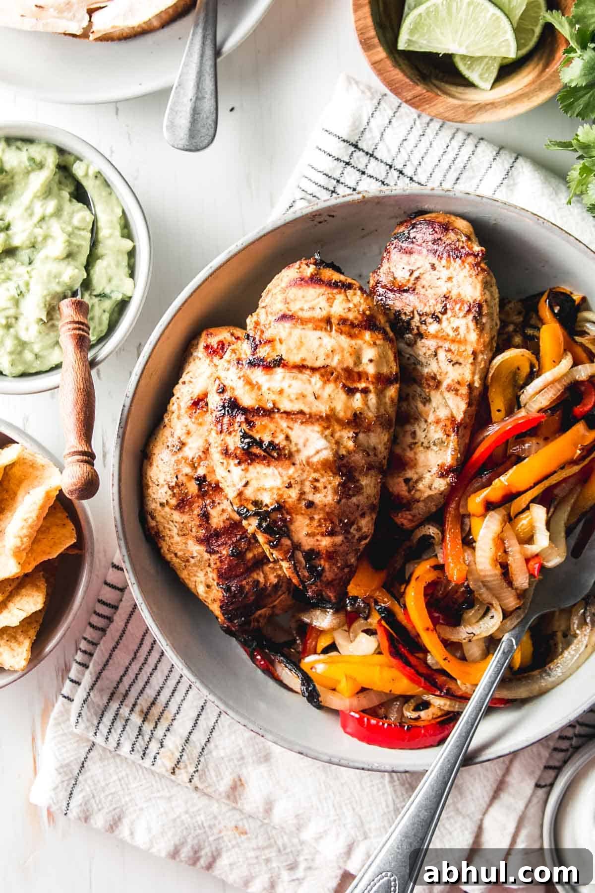 Zesty Mexican Citrus Marinade for Juicy Chicken 2 Mexican citrus marinated chicken breasts in a bowl with grilled bell peppers and onions.