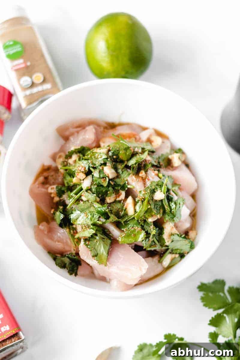 Zesty Mexican Citrus Marinade for Juicy Chicken 4 Fajita marinade with lots of cilantro over chicken strips in a white bowl.