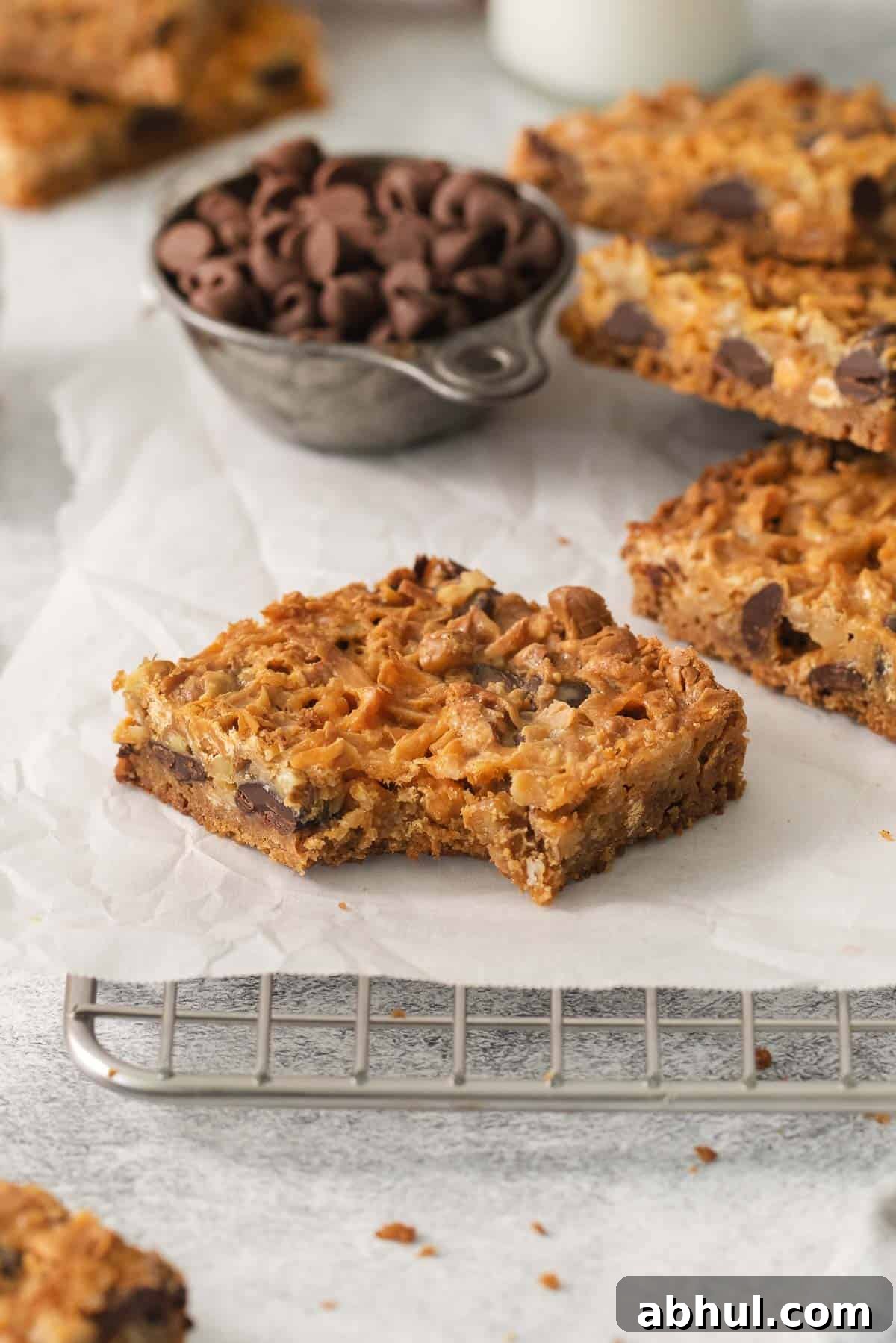 Gluten-Free Seven-Layer Bars Recipe — Chewy Chocolate Coconut Bars 11 7-layer bars on a cooling rack with bite taken out