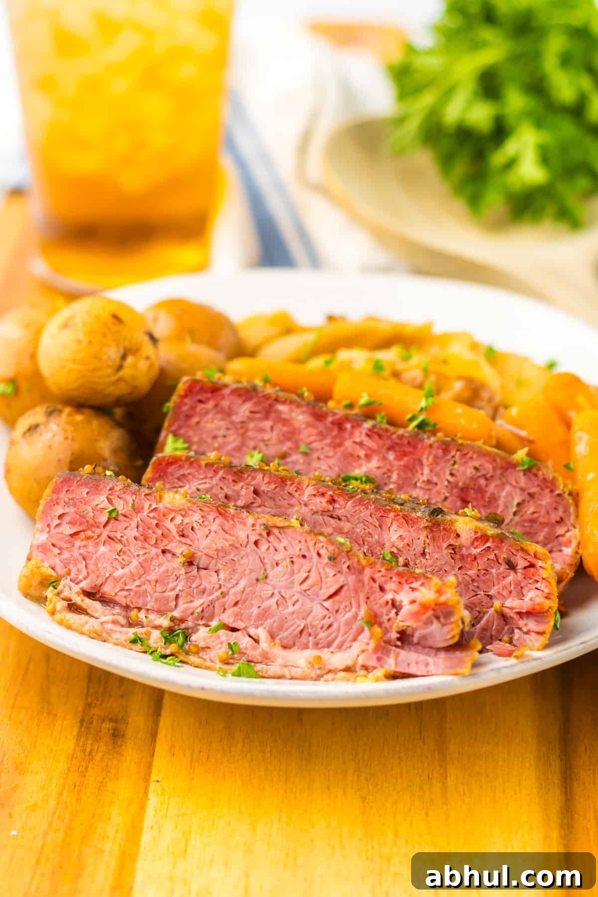 Slices of corned beef brisket, baby potatoes, and baby carrots on a white plate.