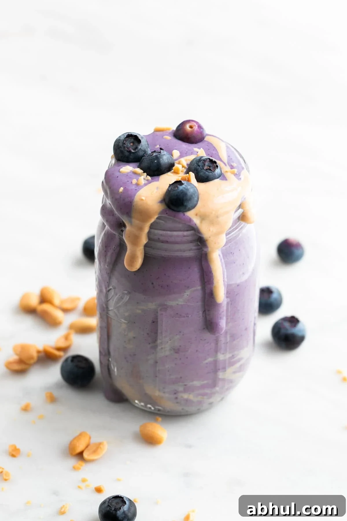 Silken tofu smoothie in a jar with a topping of blueberries, peanut butter, and chopped peanuts.