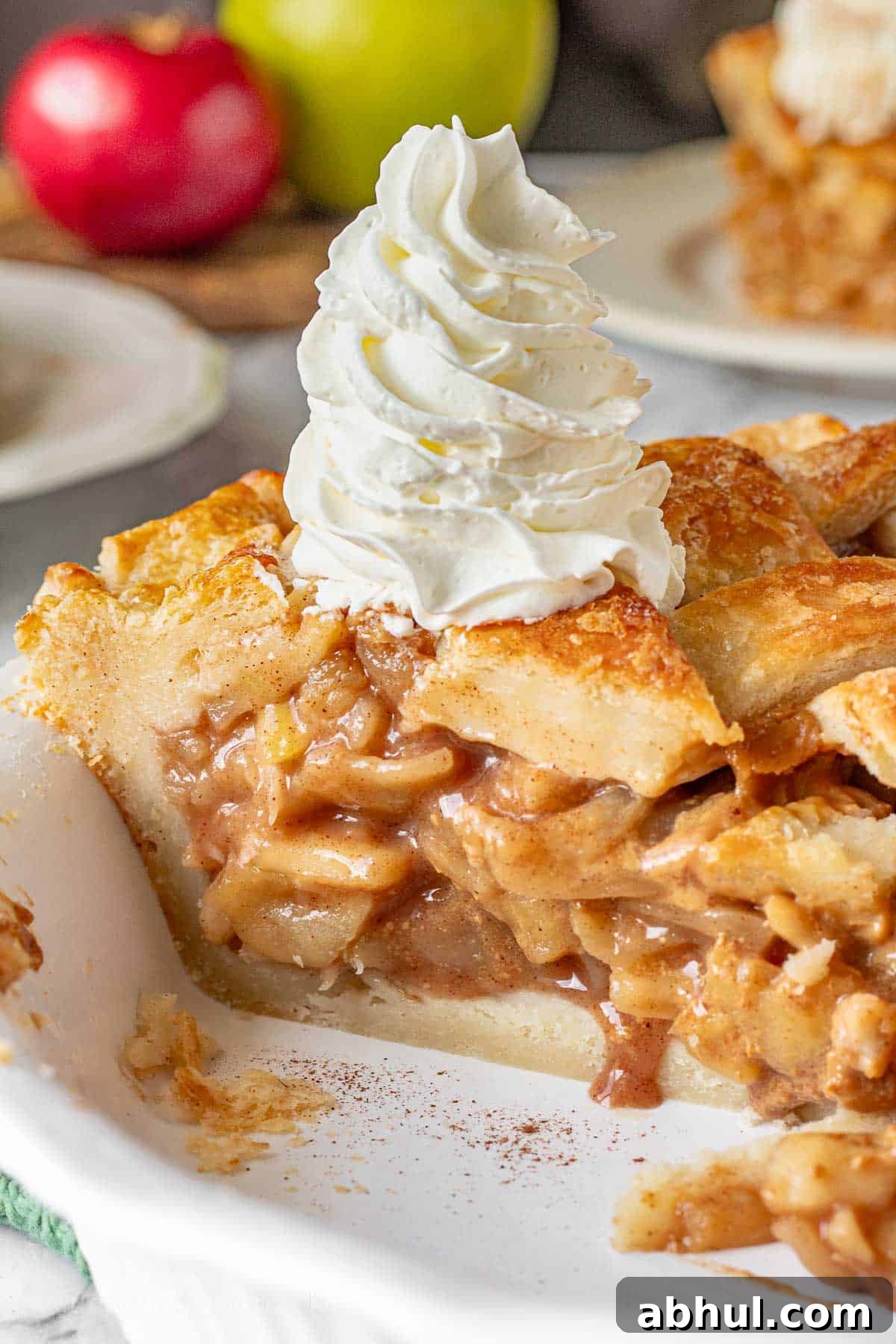Baked caramel apple pie slice with tall whipped cream.