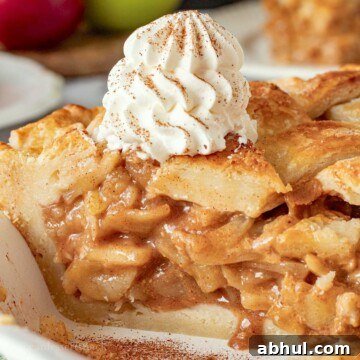 Baked caramel apple pie slice with whipped cream on top.