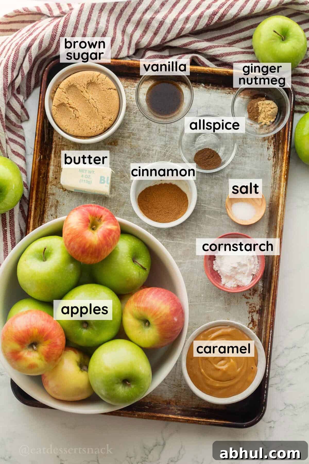 Labeled ingredients for caramel apple pie in glass dishes on metal baking pan.