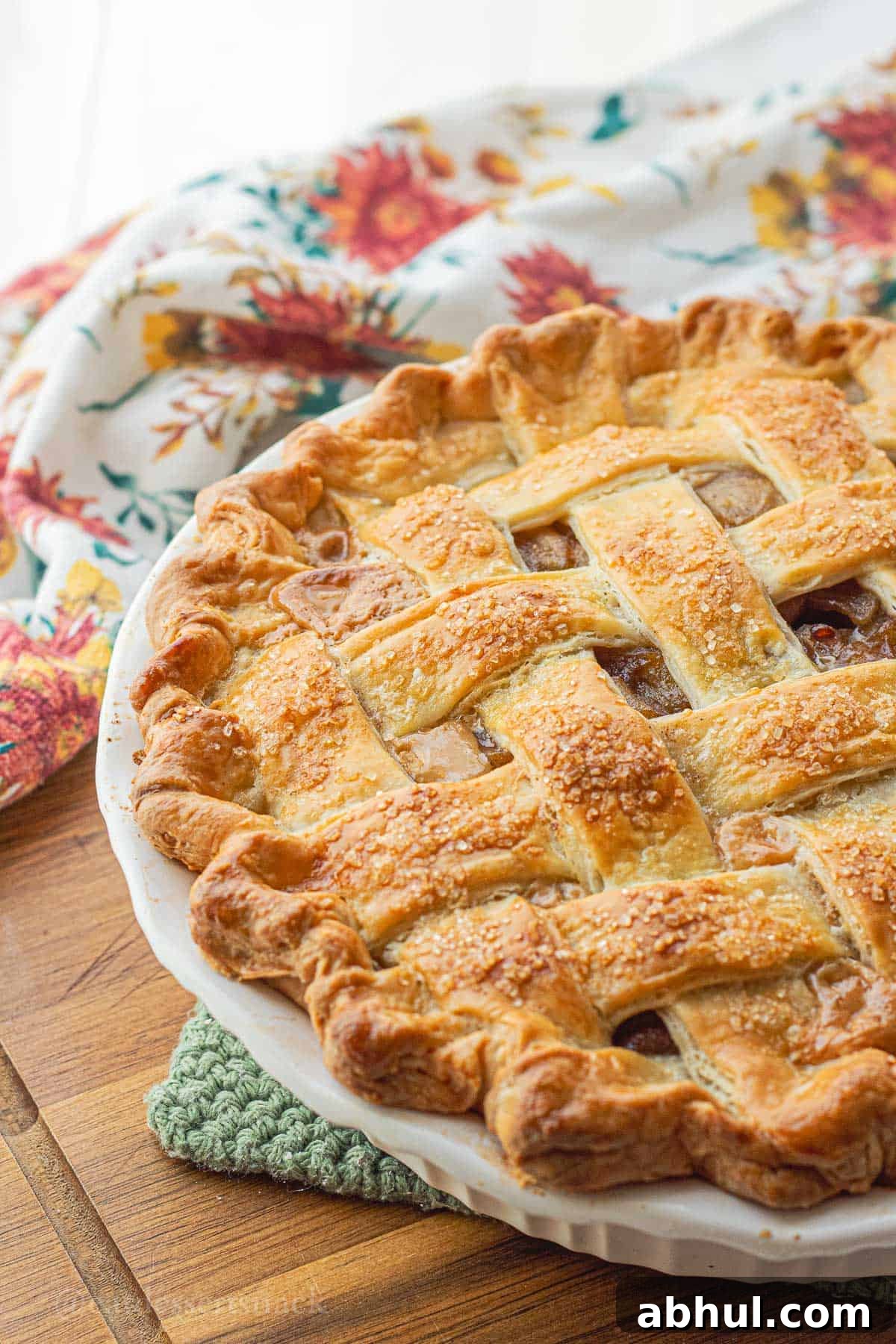 Baked unsliced dulce de leche apple pie in white pie pan.