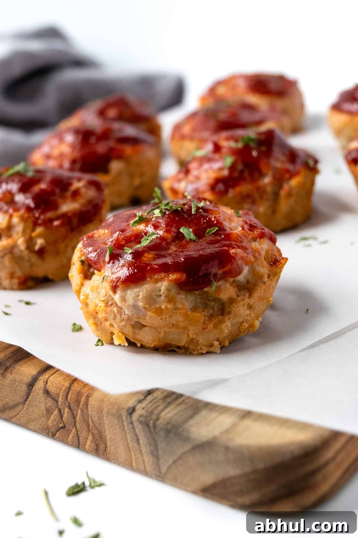 Turkey Meatloaf Muffins on a wood cutting board with parchment paper.